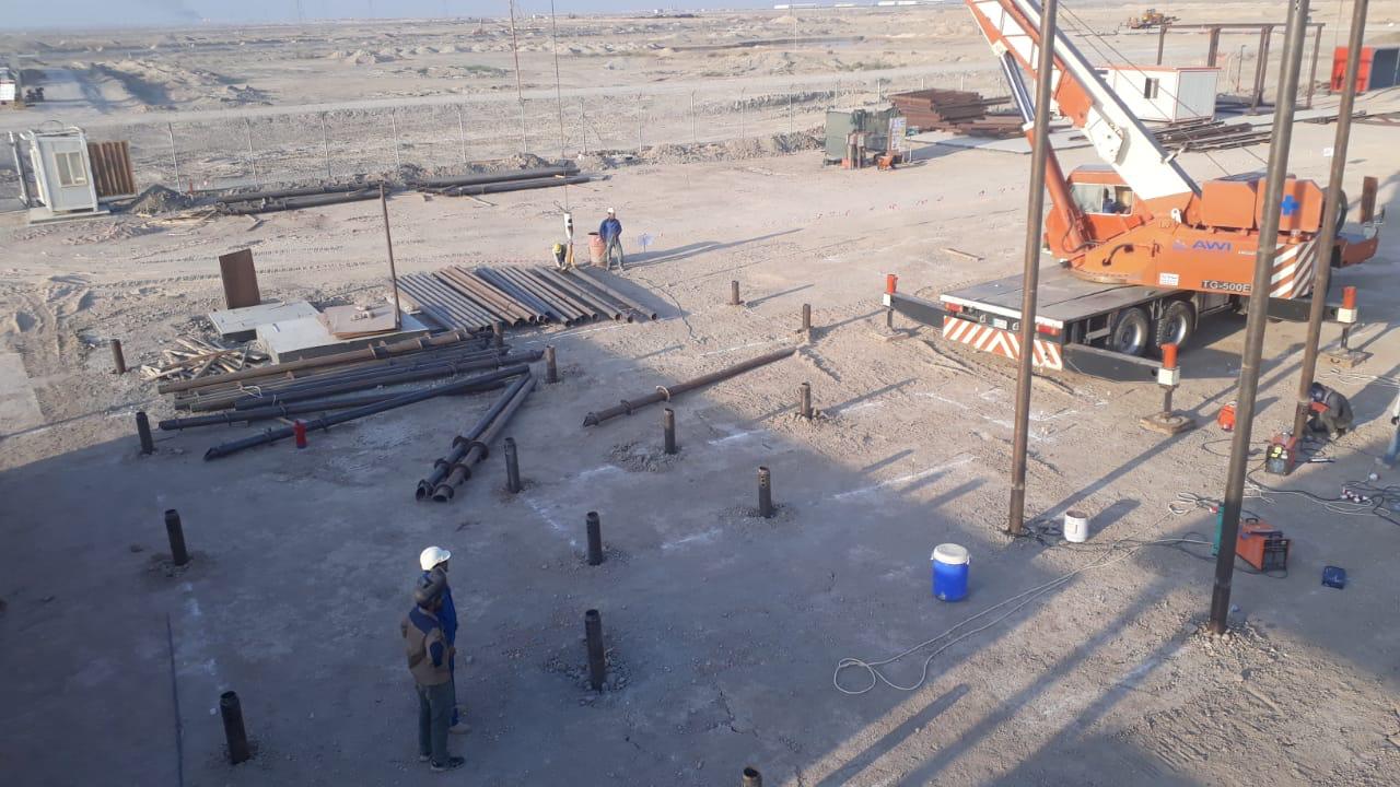 Installation de pieux vissés par grue dans un champ pétrolier à Basra, Irak