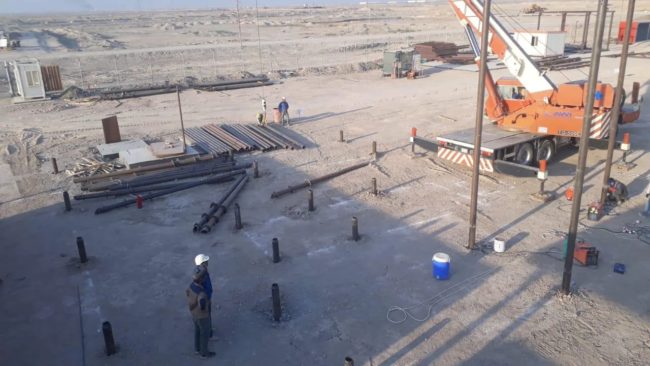 Schraubpfahl-Installation mit Kran auf dem Ölfeld Basra, Arbeiter positionieren Schraubpfähle unter Wüstenbedingungen